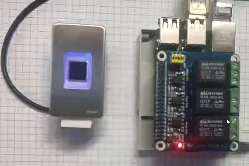 The same fingerprint scanner beside a Raspberry Pi carrying a multi-channel relay board with screw terminals.
